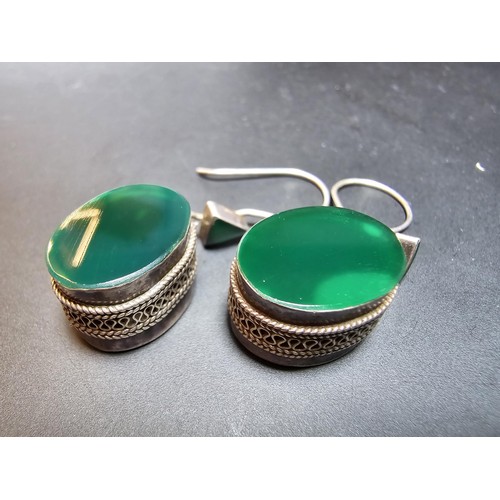 207 - A pair of large ornate and unusual sterling silver drop earrings featuring a polished green glass in... 