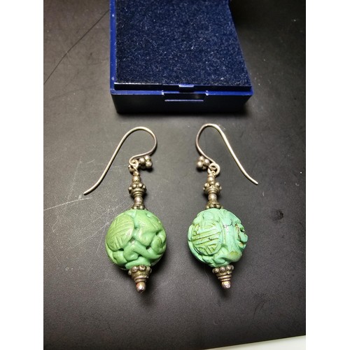 201 - An ornate vintage pair tested as sterling silver drop earrings featuring carved green turquoise ston... 