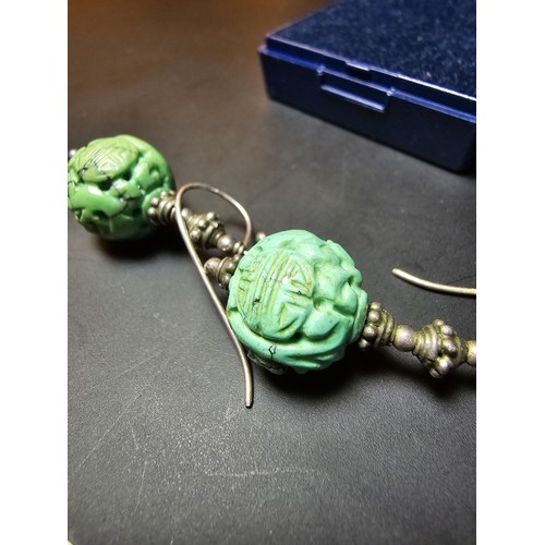 201 - An ornate vintage pair tested as sterling silver drop earrings featuring carved green turquoise ston... 