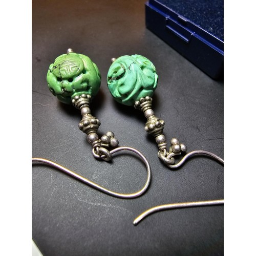 201 - An ornate vintage pair tested as sterling silver drop earrings featuring carved green turquoise ston... 