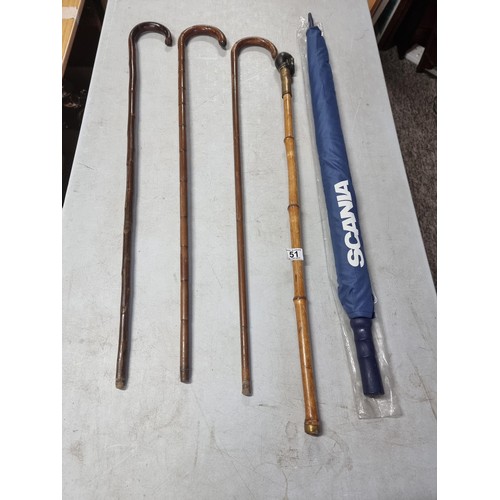 51 - A collection of 4x walking sticks and an unused Scania Umbrella. 1x of the sticks has a brass top in... 