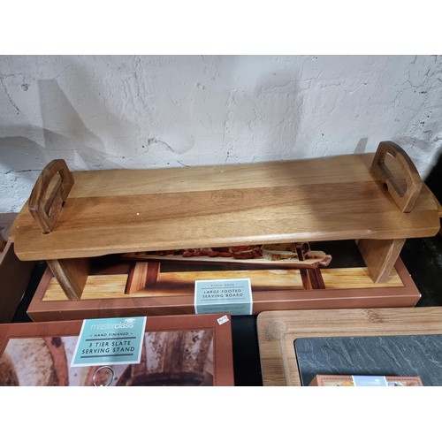 14 - A collection of boxed Masterclass display stands including an Acacia wood large footed serving wood,... 