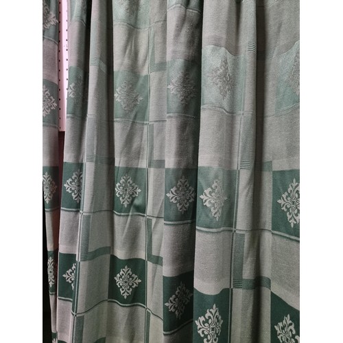 33 - A pair of green check curtains with a crest style  design on a brass curtain rail complete with hook... 