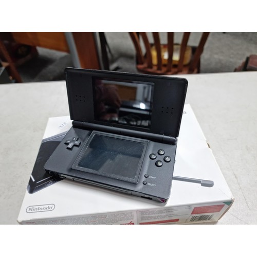 15 - A boxed Nintendo DS lite in black and grey along with its charger along with 4 boxed games.