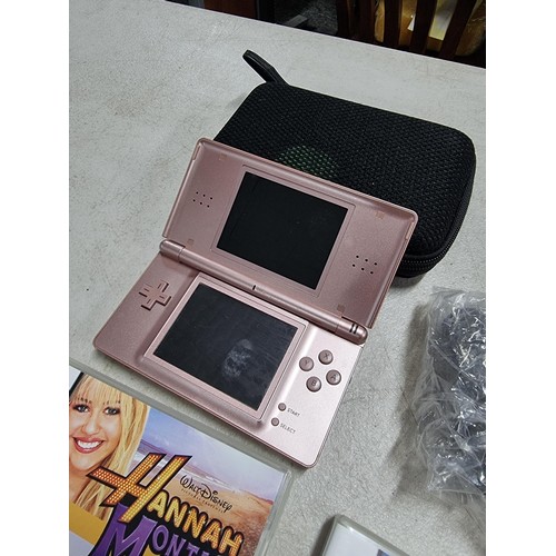 18 - A cased Nintendo DS lite in pink complete with charger and a quantity of 4 games including Hannah Mo... 