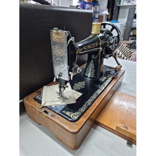 27 - A cased Singer manual sewing machine No: EG818354 with a quantity of accessories in a fitted case.