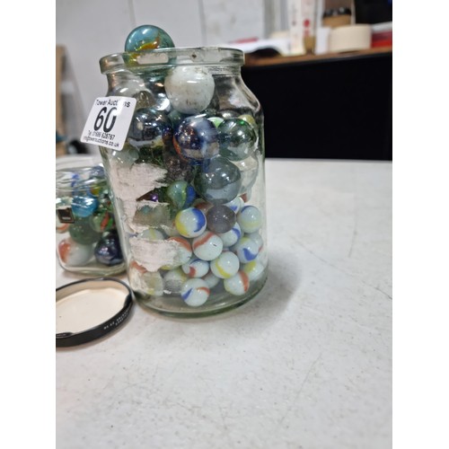 60 - 2x jars containing a large quantity of collectable marbles inc a large quantity of blue yellow and w... 