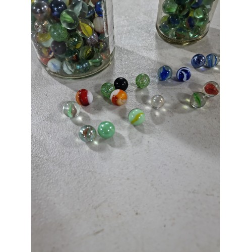 49 - 2x Jars of marbles of various designs inc iridescent marbles, green and white marbles etc, please se... 