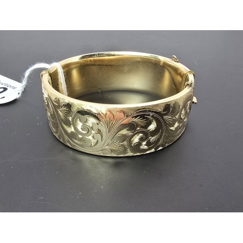 259 - A good quality ornate chunky rolled gold hinged bangle featuring an ornate engraved design on one si... 