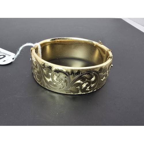 259 - A good quality ornate chunky rolled gold hinged bangle featuring an ornate engraved design on one si... 