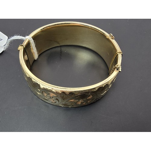 259 - A good quality ornate chunky rolled gold hinged bangle featuring an ornate engraved design on one si... 