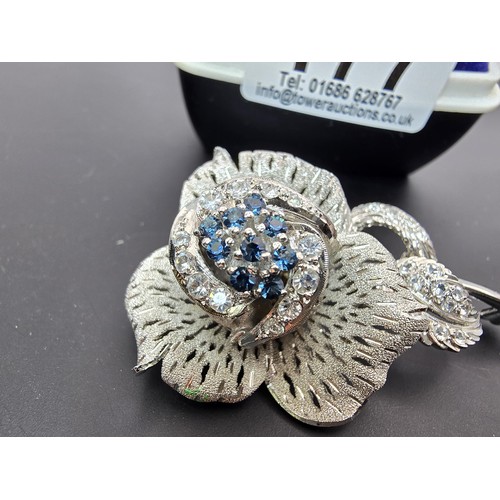 177 - A very pretty ornate silver tone rose formed brooch inset with blue crystals and clear crystals, the... 