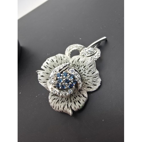 177 - A very pretty ornate silver tone rose formed brooch inset with blue crystals and clear crystals, the... 