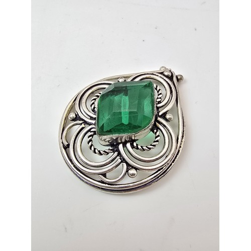 197 - A large ornate tested as silver pendant with a pierced design inset with a large faceted green cryst... 