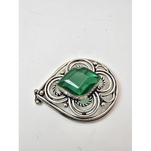 197 - A large ornate tested as silver pendant with a pierced design inset with a large faceted green cryst... 