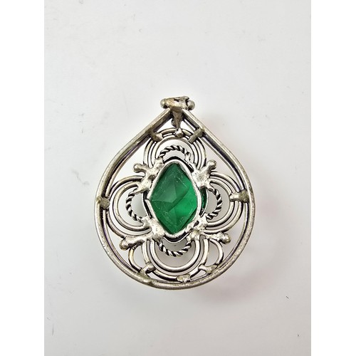 197 - A large ornate tested as silver pendant with a pierced design inset with a large faceted green cryst... 