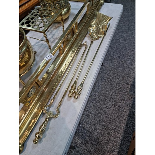 313 - Large collection of brass items inc a large brass ornate fender with paw feet style corners, tall br... 