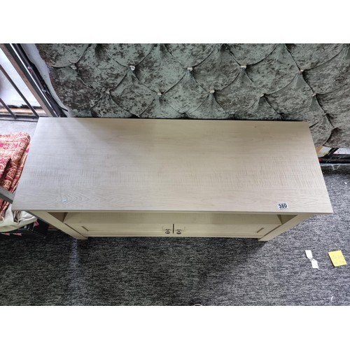 380 - Good quality wooden cream coloured TV unit with shelf to the front and two doors beneath, in good ov... 