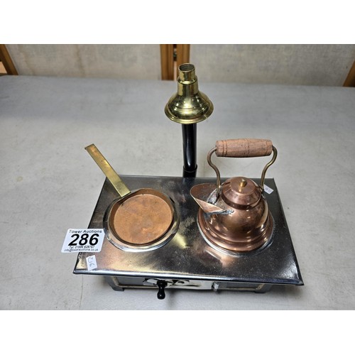 286 - A miniature metal operational stove featuring a copper kettle and a copper frying pan an 2 burners o... 