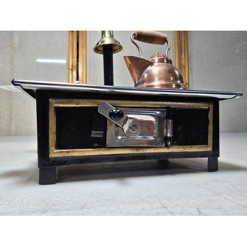 286 - A miniature metal operational stove featuring a copper kettle and a copper frying pan an 2 burners o... 