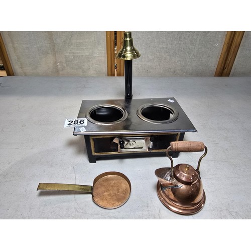 286 - A miniature metal operational stove featuring a copper kettle and a copper frying pan an 2 burners o... 