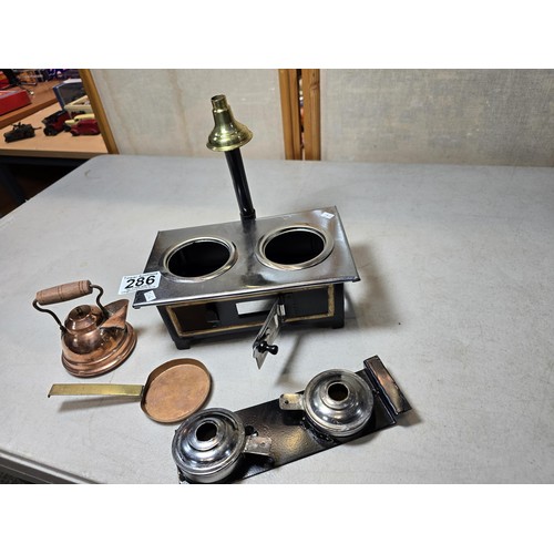 286 - A miniature metal operational stove featuring a copper kettle and a copper frying pan an 2 burners o... 