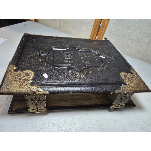 294 - A large antique family holy bible with a black leather hard cover featuring gilt and ornate corners ... 