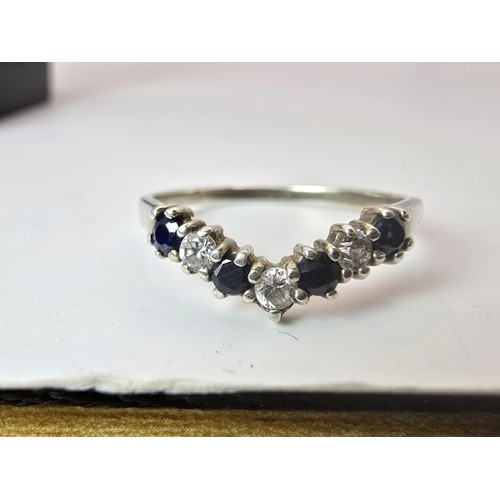 219 - An ornate 925 silver wishbone ring inset with 4 sapphire stones and 3 sparkly CZ stones. The ring is... 