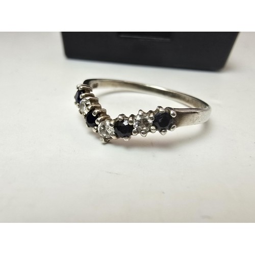 219 - An ornate 925 silver wishbone ring inset with 4 sapphire stones and 3 sparkly CZ stones. The ring is... 