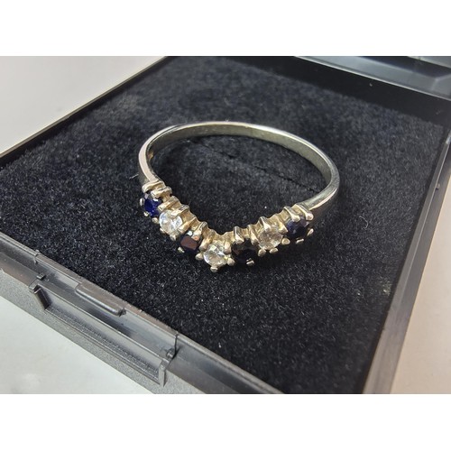 219 - An ornate 925 silver wishbone ring inset with 4 sapphire stones and 3 sparkly CZ stones. The ring is... 