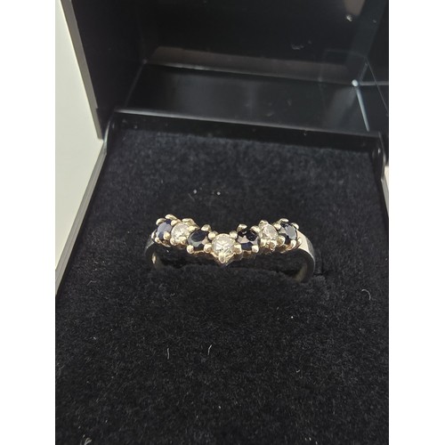 219 - An ornate 925 silver wishbone ring inset with 4 sapphire stones and 3 sparkly CZ stones. The ring is... 