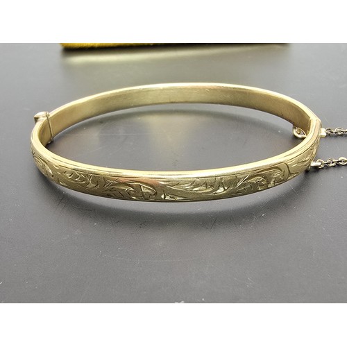 247 - A vintage 9ct yellow gold with metal core hinged bangle having an engraved design to one side, clasp... 