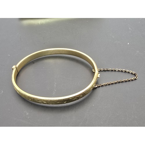 247 - A vintage 9ct yellow gold with metal core hinged bangle having an engraved design to one side, clasp... 