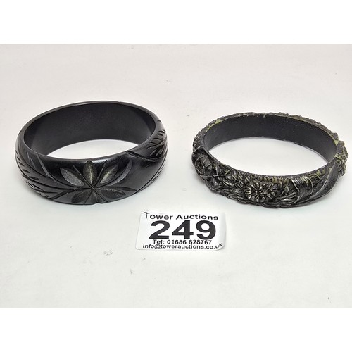 249 - 2 vintage costume bangles which includes a chunky deep carved bangle, possibly jet. Along with a bla... 