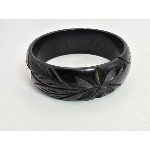 249 - 2 vintage costume bangles which includes a chunky deep carved bangle, possibly jet. Along with a bla... 