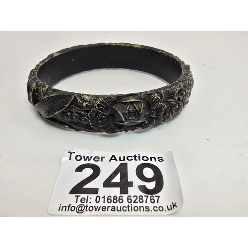 249 - 2 vintage costume bangles which includes a chunky deep carved bangle, possibly jet. Along with a bla... 