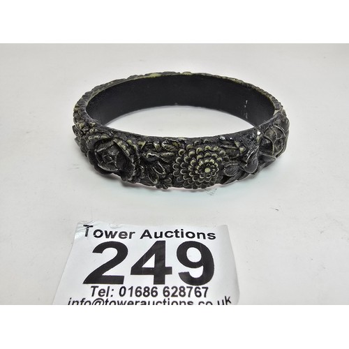 249 - 2 vintage costume bangles which includes a chunky deep carved bangle, possibly jet. Along with a bla... 