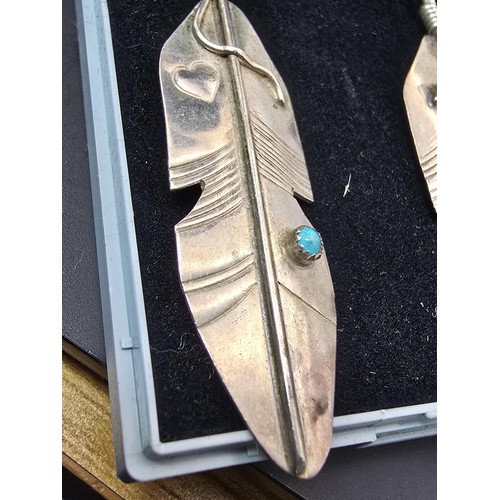 177 - A pair of large 925 silver long drop earrings in the form of Navajo feathers, inset with a turquoise... 