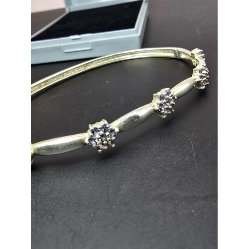 178 - A good as new 925 silver hinged bangle inset with pretty iolite gemstones, in cluster form in 5 clus... 