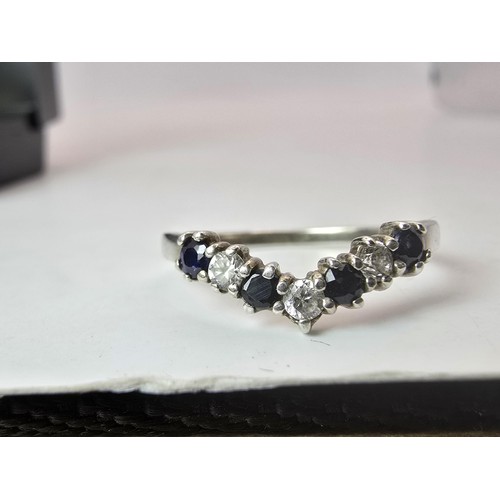 215 - An ornate 925 silver wishbone ring inset with 4 sapphire stones and 3 sparkly CZ stones. The ring is... 