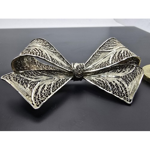 223 - A large and impressive 925 silver bow formed brooch with an intricate filigree design, the brooch di... 