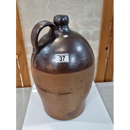 37 - Large earthenware brown whisky flagon, in dark over light brown glaze, has a chip to the handle othe... 