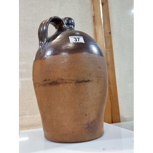 37 - Large earthenware brown whisky flagon, in dark over light brown glaze, has a chip to the handle othe... 