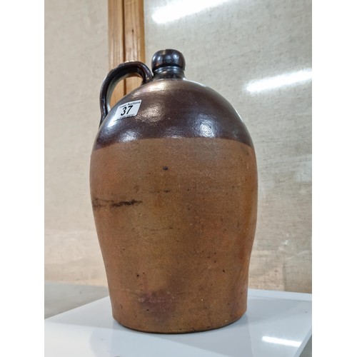 37 - Large earthenware brown whisky flagon, in dark over light brown glaze, has a chip to the handle othe... 