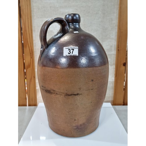 37 - Large earthenware brown whisky flagon, in dark over light brown glaze, has a chip to the handle othe... 