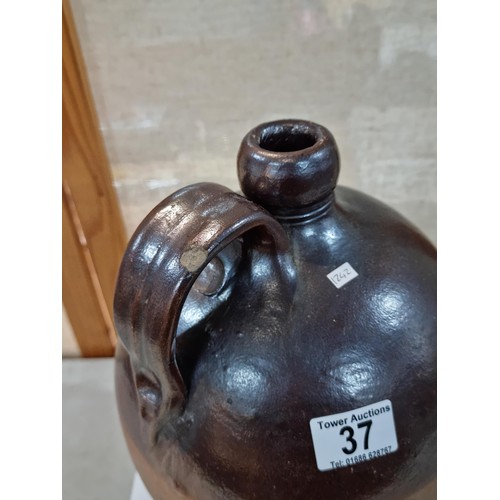 37 - Large earthenware brown whisky flagon, in dark over light brown glaze, has a chip to the handle othe... 