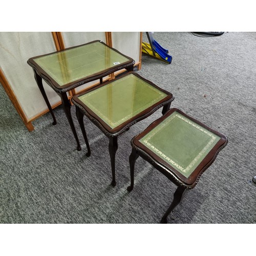451 - A nest of 3 side tables, In mahogany with a green leather inlay and glass cover. One leg loose needs... 