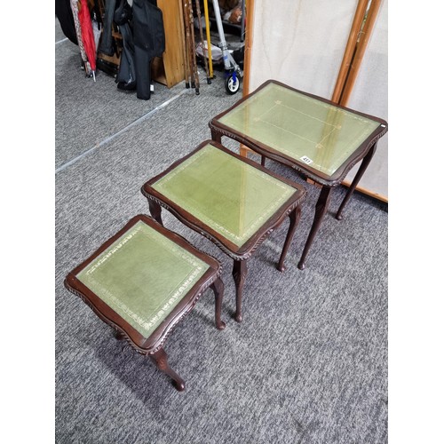 451 - A nest of 3 side tables, In mahogany with a green leather inlay and glass cover. One leg loose needs... 