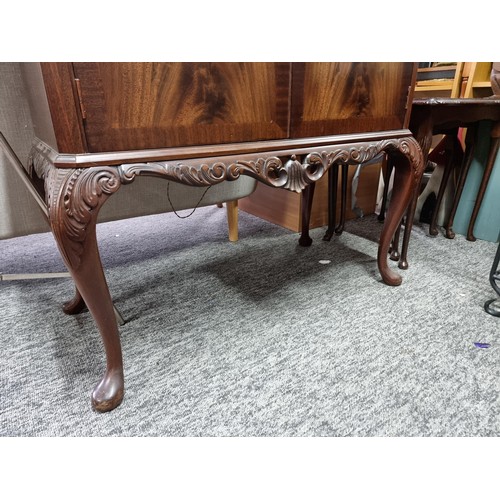 453 - A good quality reproduction drinks cabinate, featuring double flamed mahogany doors revealing a divi... 