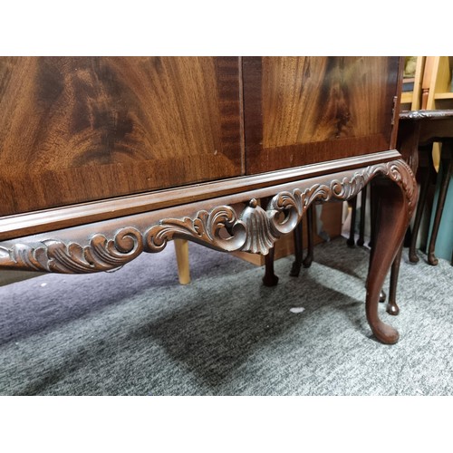 453 - A good quality reproduction drinks cabinate, featuring double flamed mahogany doors revealing a divi... 